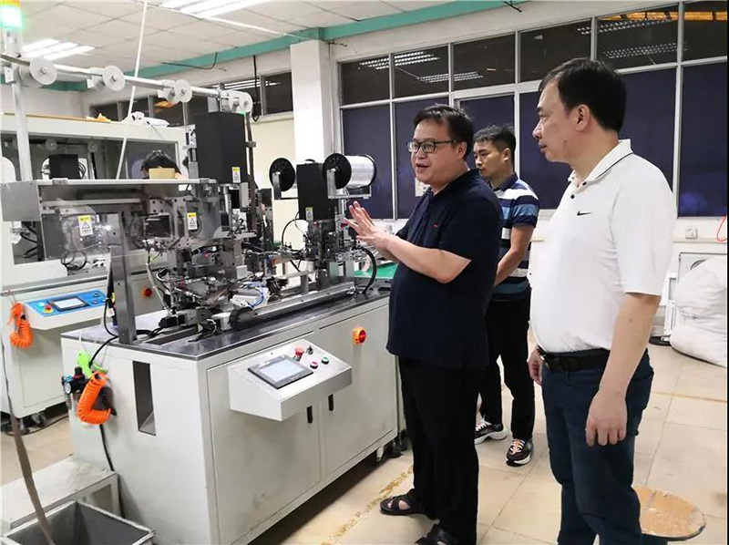 华圣达技术设备中心研发人员（左一）在介绍自主研发的智能生产拉链机械设备